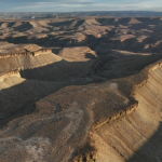 Utah approved blasting 100-foot canyon cliffs to widen a 5.3-mile road for oil trucks; after two earlier plans failed, a new federal lawsuit says 47 historic sites and 19th-century inscriptions are at risk